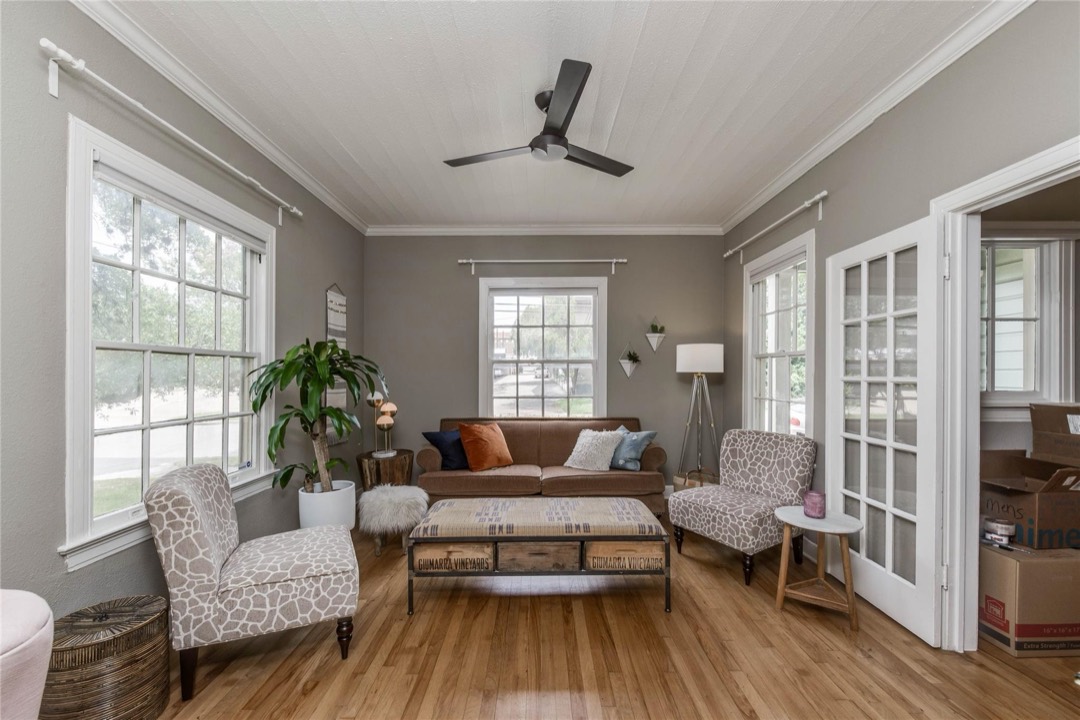 Bright, spacious living room with ceiling fan and large windows