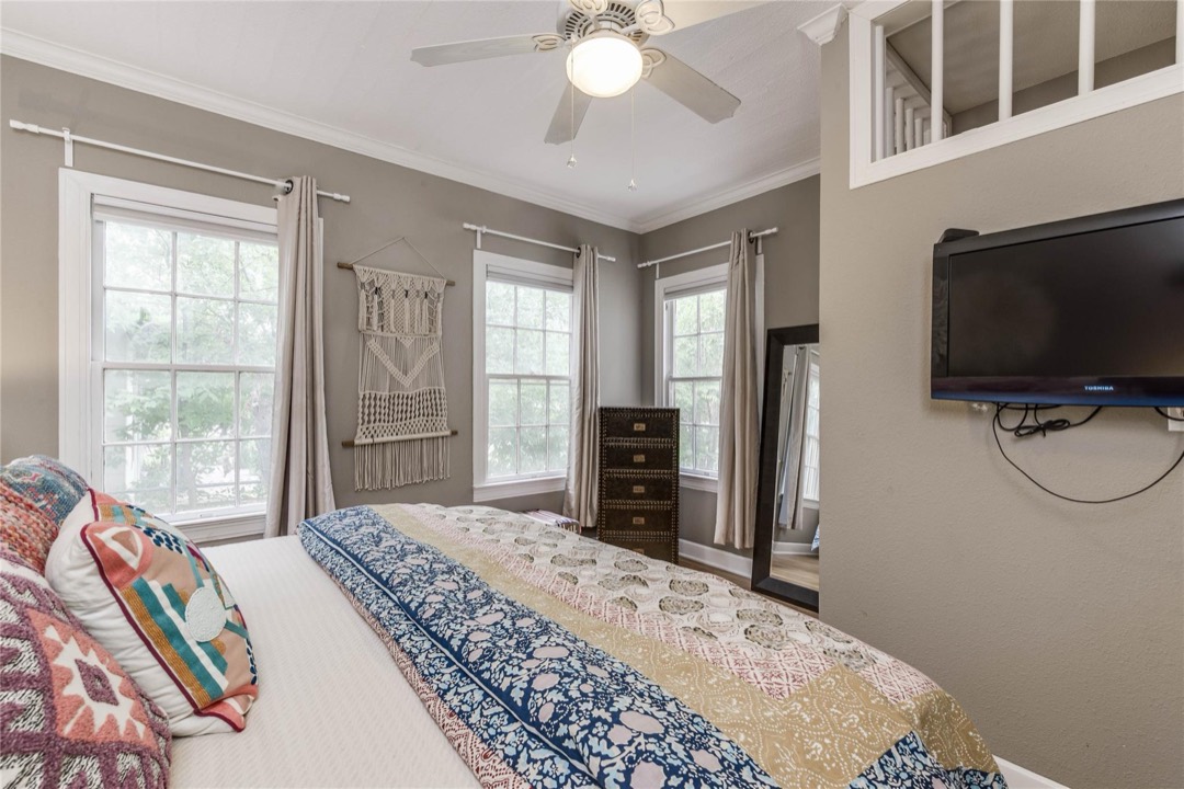 Bright master bedroom with ceiling fan and multiple windows
