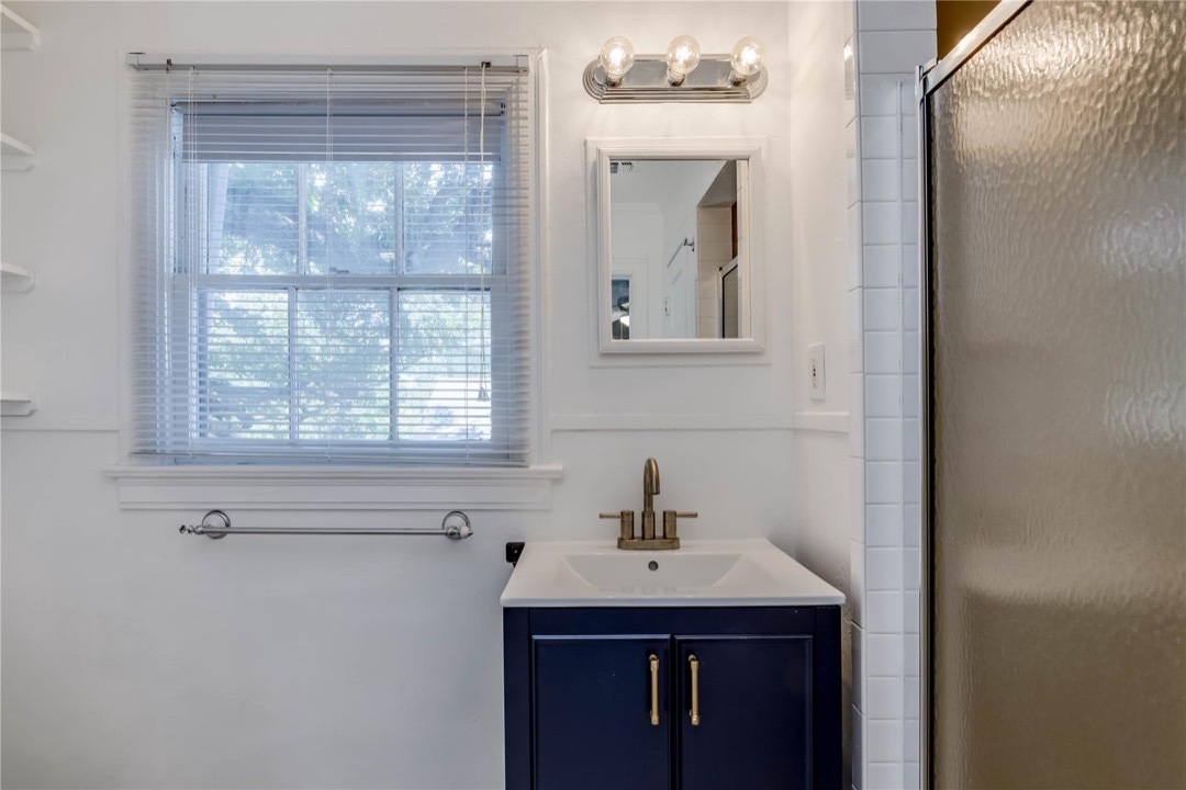 Renovated bathroom with modern navy vanity, gold fixtures and subway tile