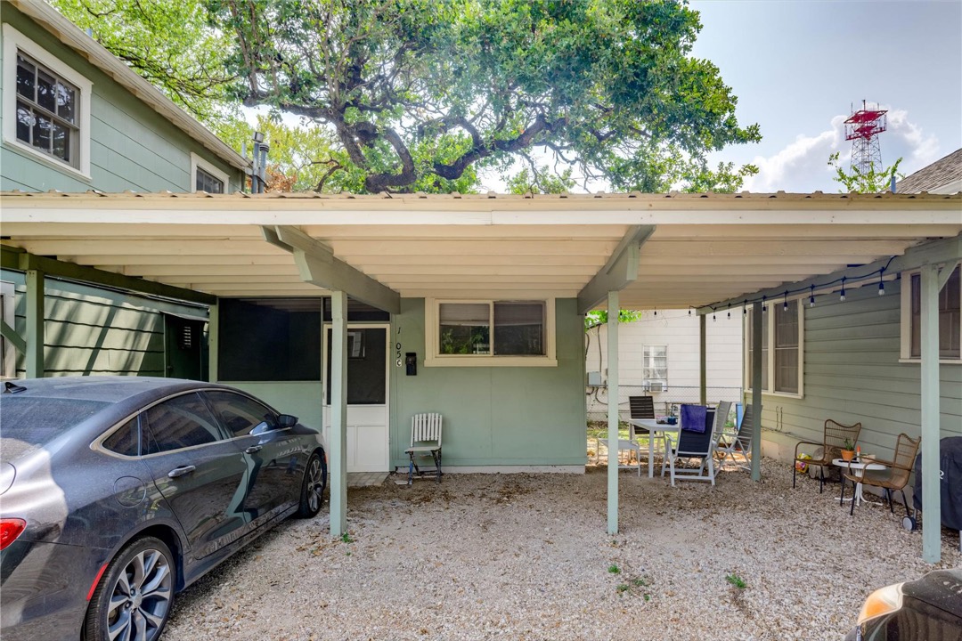 Covered carport and outdoor seating area shaded by a large oak tree