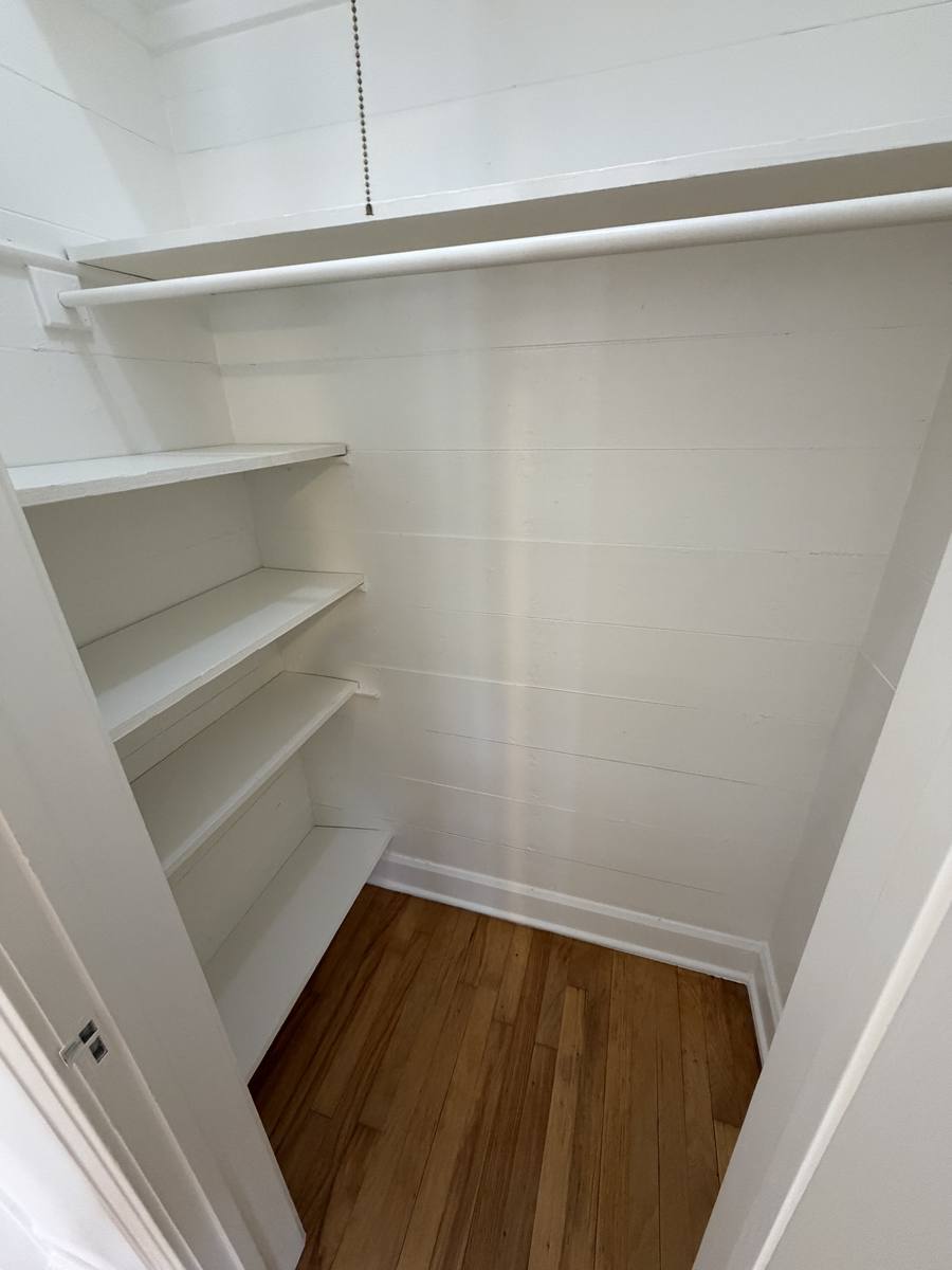 Walk-in closet in Unit D with shelving and a full-length hanging rod