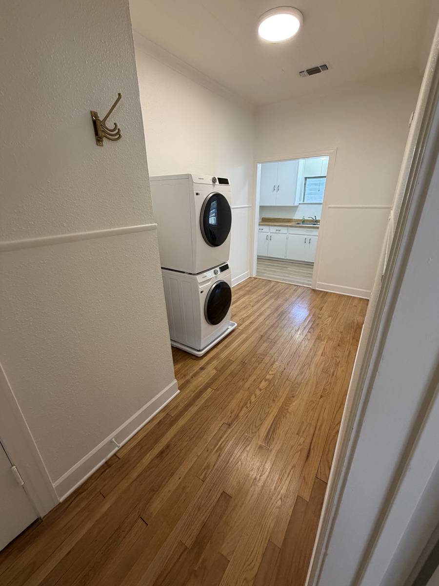 In-unit stacked washer and dryer in Unit D, with the kitchen visible beyond