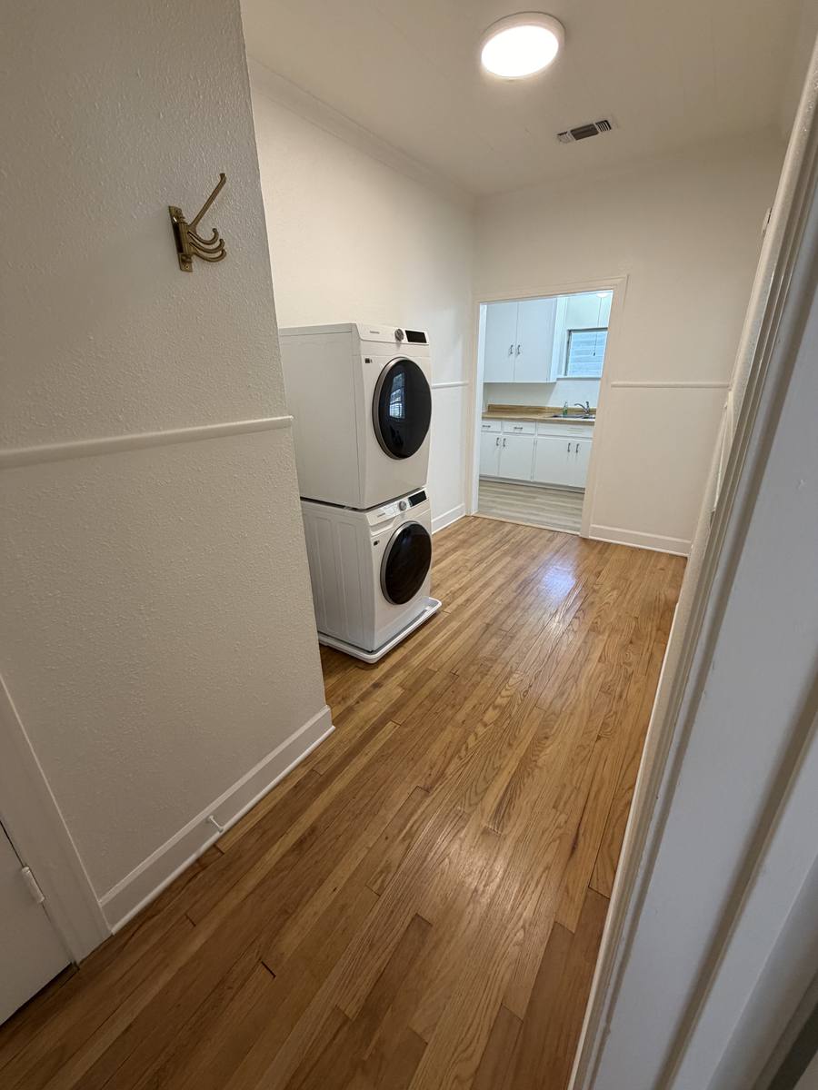 Stacked in-unit washer and dryer in Unit D with the kitchen beyond